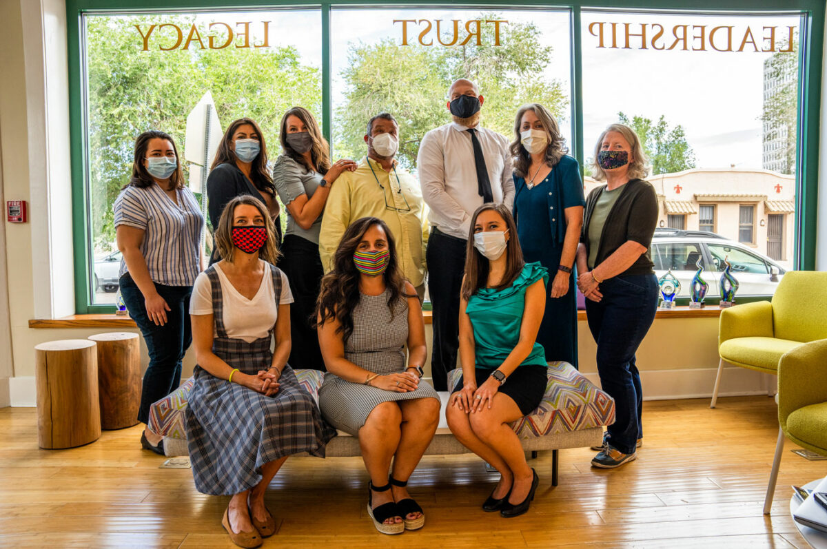 Albuquerque Community Foundation with masks on posing for a group photo in the organizations lobby.