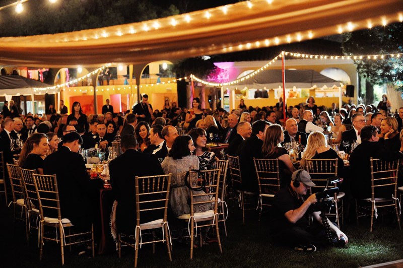 People eating outdoors at a black tie event