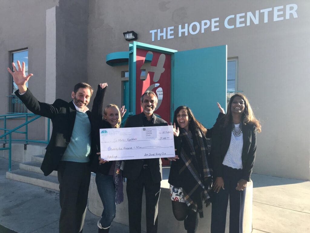 Group of people holding an oversized check in front of The Hope Center