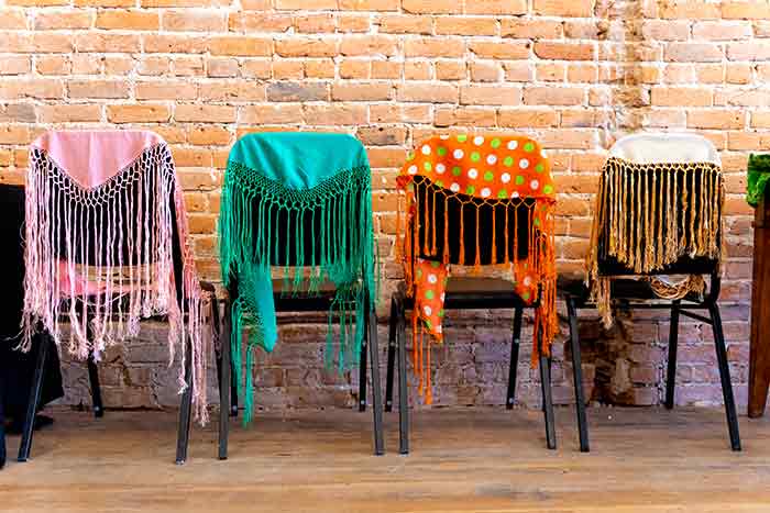 Multi-colored shawls draped over chairs
